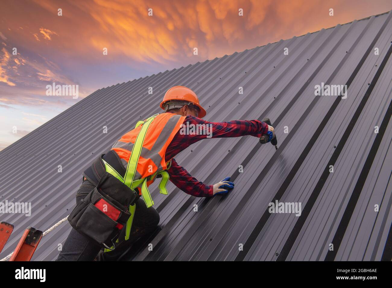 Bauarbeiter Montage von Metallblechen auf einem Dach, Thailand Stockfoto