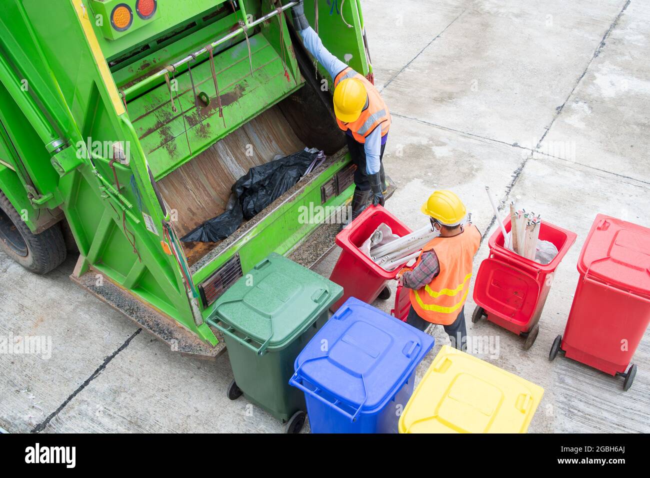 Zwei Müllmänner stehen neben einem Mülltonne-LKW, der Mülltonnen entleert, Thailand Stockfoto