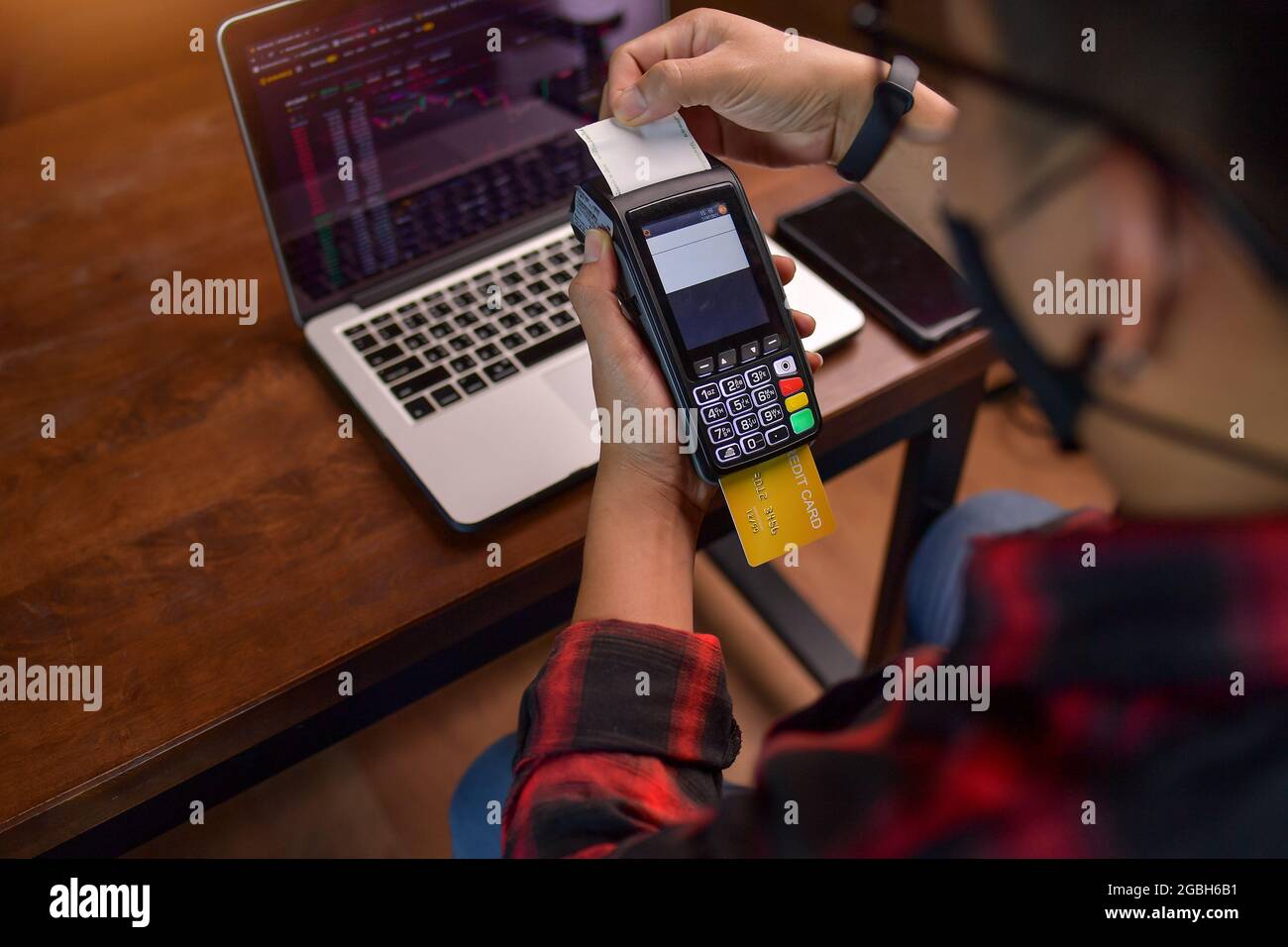 Mann, der an einem Tisch sitzt und eine kontaktlose Zahlung mit einem Kreditkartenleser abgibt Stockfoto