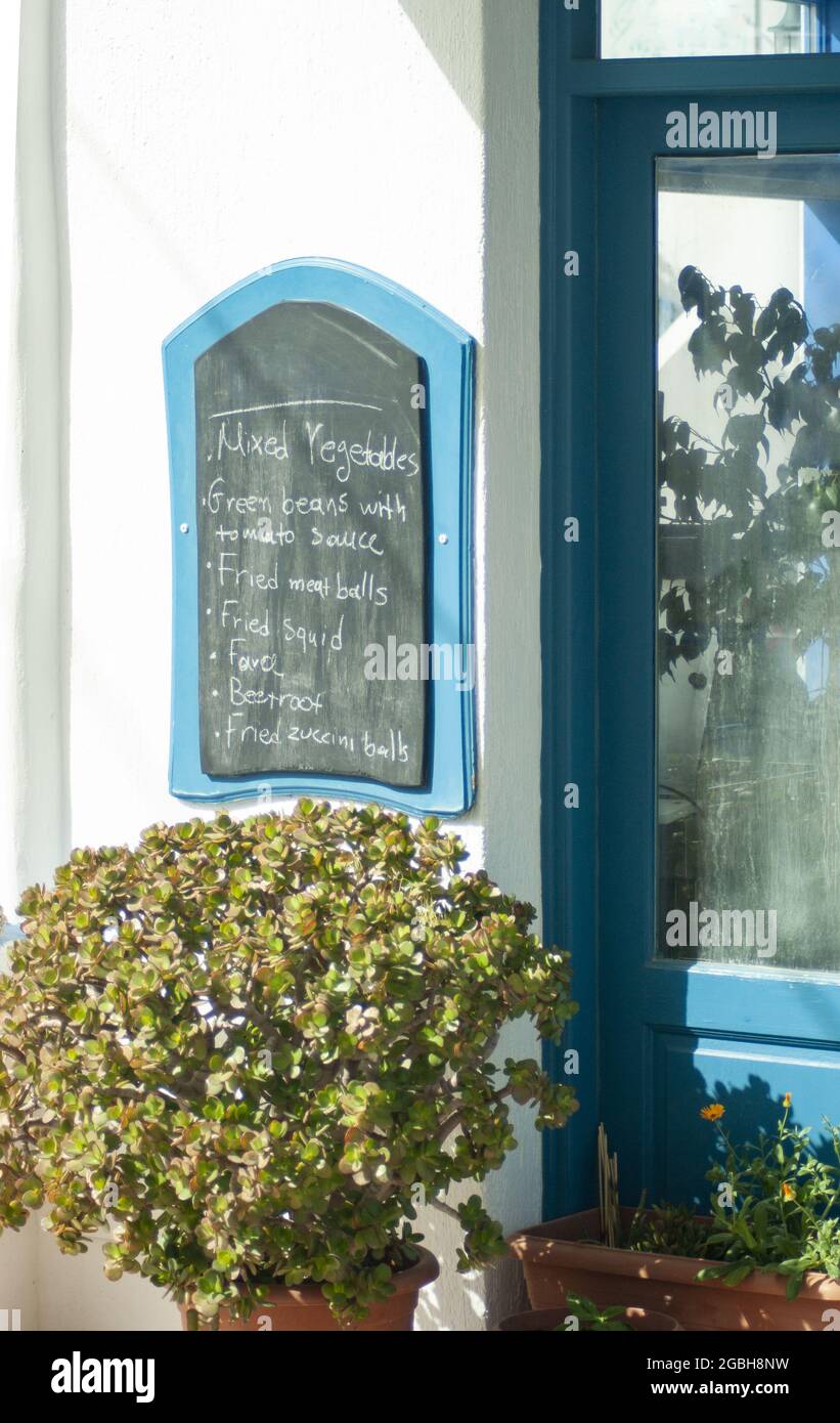 Kleine griechische Taverne, Insel Anafi, Griechenland. Authentisches Restaurant mit traditioneller Speisekarte. Auf einer Kreidetafel. Vertikale Aufnahme, mit Kopierplatz. Stockfoto