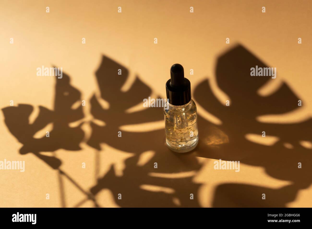 Eine Tropfflasche aus transparentem ätherischem Öl mit Goldteilen. Konzept der Naturkosmetik Stockfoto