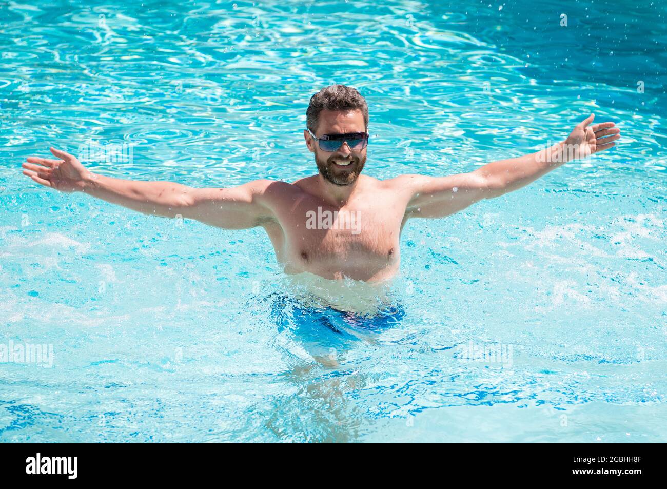 Glücklicher, gutaussehender Mann in einer Brille, der im Sommer, im Urlaub im Pool schwimmte Stockfoto
