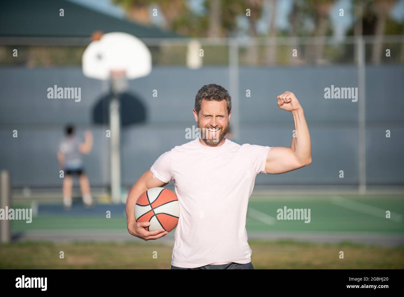 Sommer-Aktivität. Glücklich muskulösen Mann mit Basketballball. Sporttrainer oder Basketballspieler Stockfoto