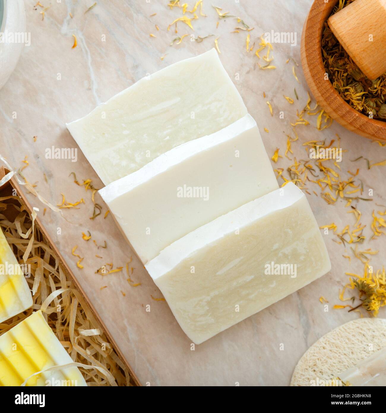 Handwerk handgemachte Seifenstücke mit Kräutern getrockneten Blumen. Natürliche Badeprodukte mit trockenen Ringelblumen für die Körper-Spa-Hautpflege. Hygieneartikel. Quadratisch Stockfoto