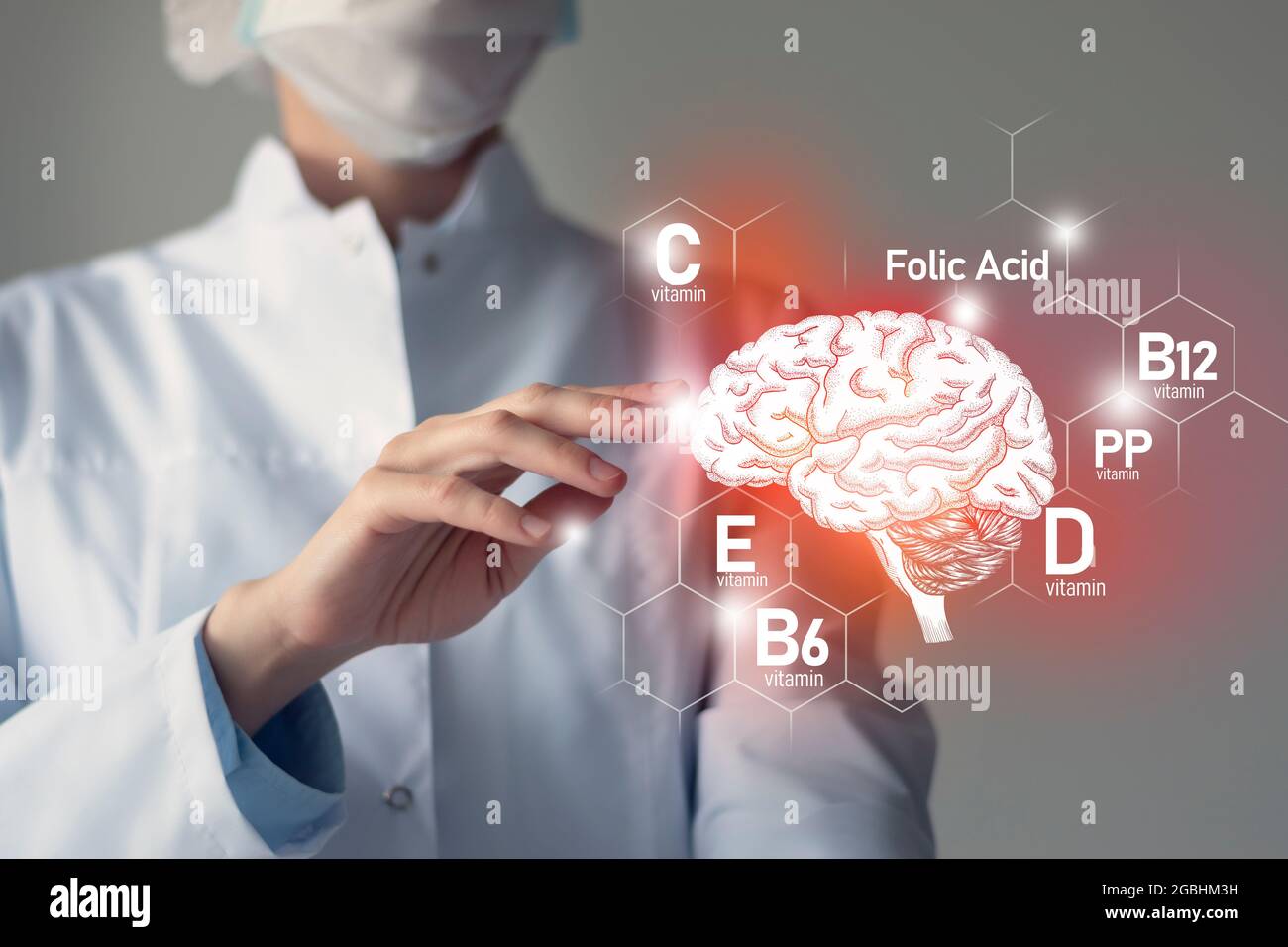 Essentielle Nährstoffe für die Gesundheit des Gehirns, einschließlich Vitamin C, Vitamin B, Folsäure, Vitamin PP. Verschwommenes Porträt eines Arztes, der das hervorgehobene Gehirn hält. Stockfoto