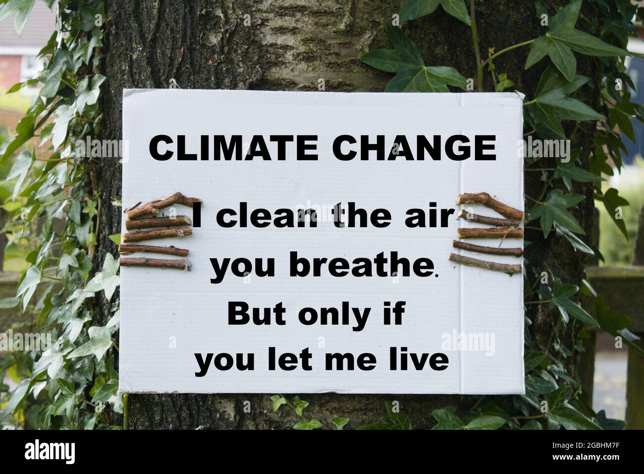 Baum mit einem Schild mit der Aufschrift „Klimawandel, ich reinige die Luft, die du atmest. Aber nur, wenn du mich leben lässt.“ Umweltschutz und seine Wirkung Stockfoto