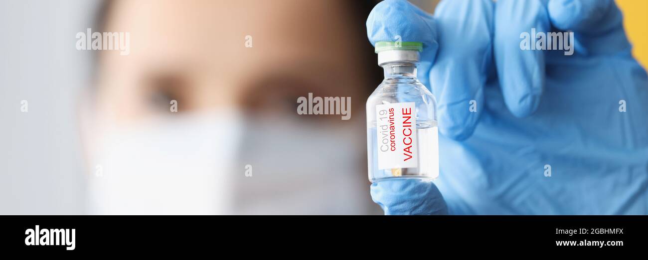 Arzt trägt Schutzmaske und Handschuhe hält Flasche covid-19 Impfstoff Stockfoto
