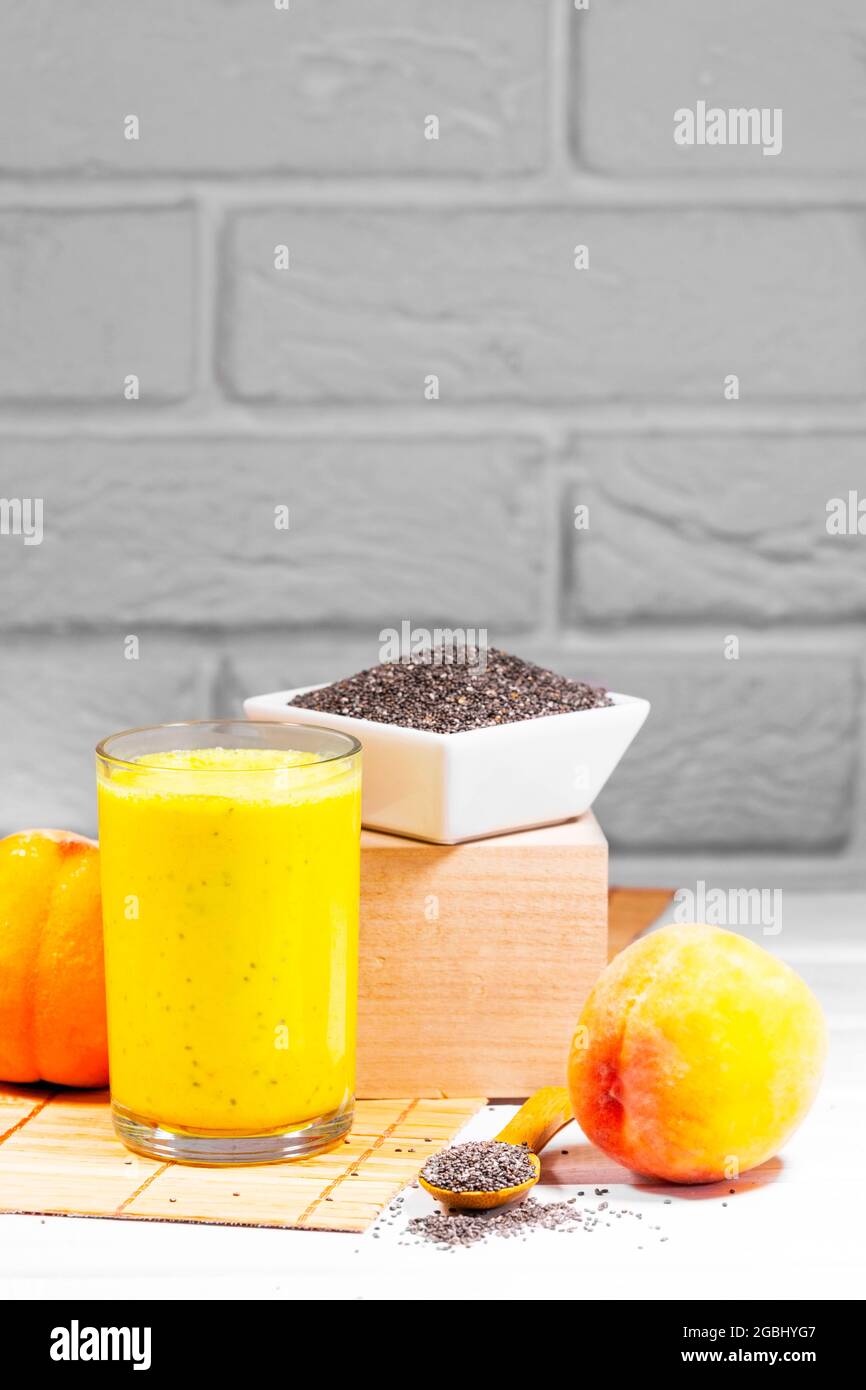 Stillleben mit Frucht-Smoothie, Pfirsich- und Chiasamen auf weißem Backstein-Hintergrund, vertikaler Auflösung, gesunder Sommerdiät, Copy Space Stockfoto