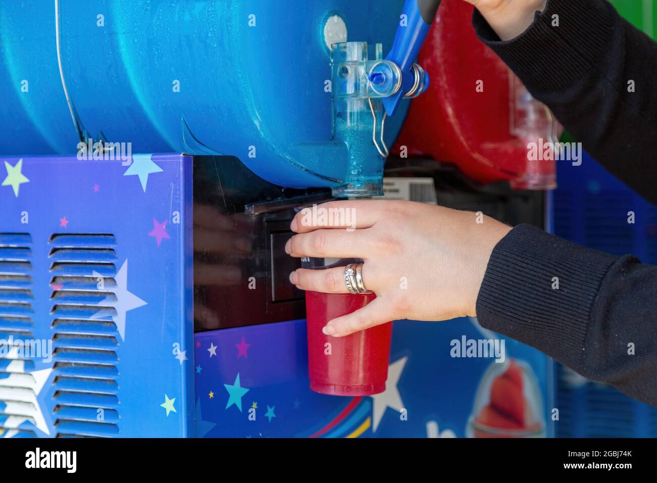 Ein Slushie-Getränk oder ein Eisgetränk eines Slush-Welpen, das aus einer Maschine in einen Plastikbecher gegossen wird Stockfoto