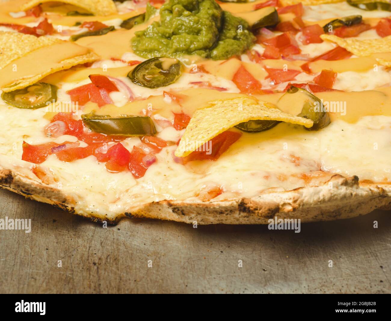 Nahkur einer Pizza mit Nachos und Avocado-Dip Stockfoto