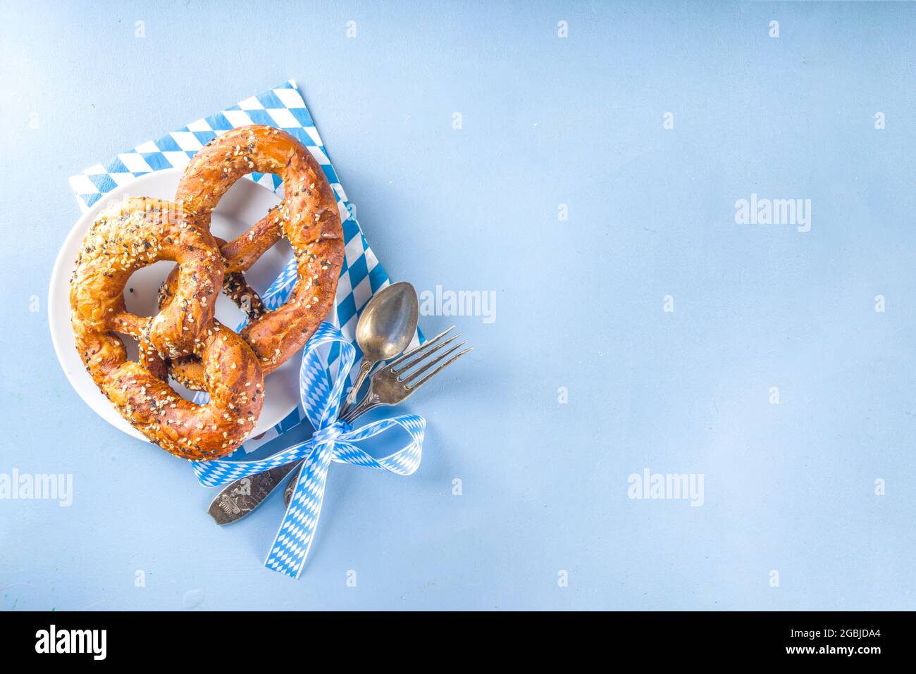 Konzept für das Oktoberfest. Oktoberfest-Tischunterlage, Teller-Gabellöffel mit traditioneller Serviette, serviert auf der Veranstaltung, Barmenü flach, farbenfroh blau Stockfoto