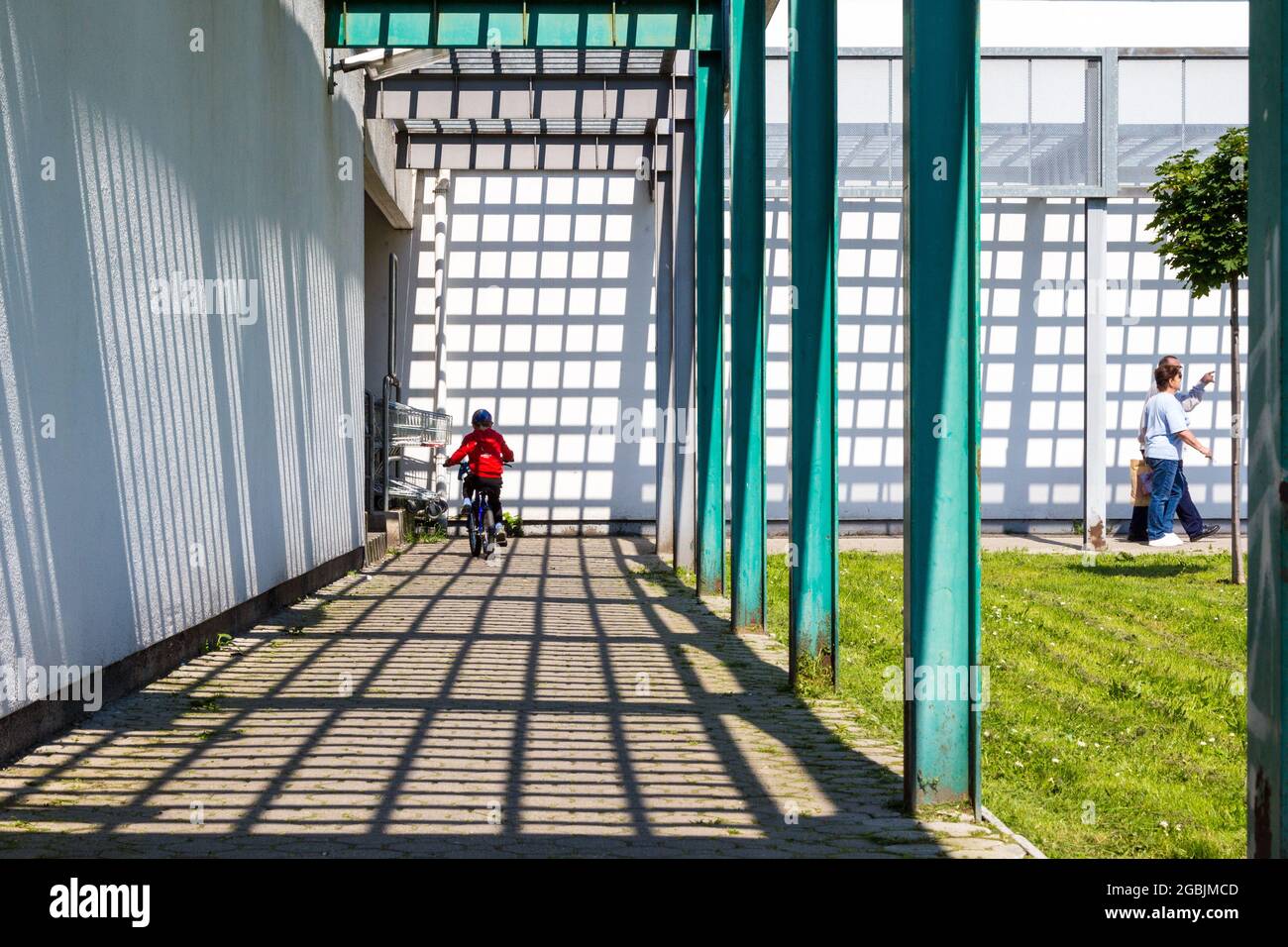 Schatten der Metallgitter Dach der modernen Korridor mit Metall Säulen und Radfahren Kind Stockfoto