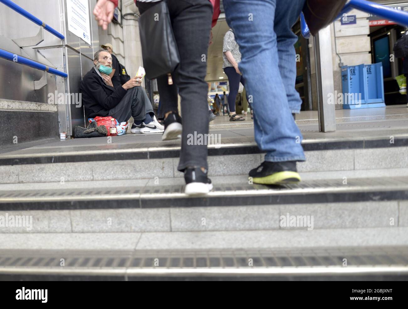London, England, Großbritannien. Victoria Station: Ein obdachloser Mann in einer COVID-Gesichtsmaske, der auf den Stufen von der U-Bahn-Station aus bettelte Stockfoto