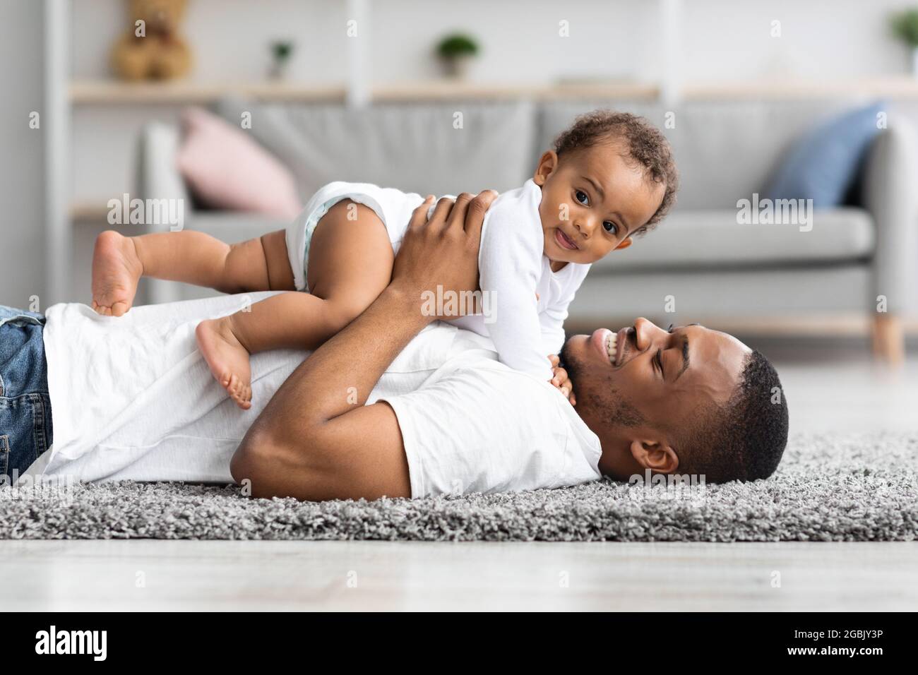 Glück der Vaterschaft. Fröhlicher junger schwarzer Vater, der Zeit mit Kleinkind genießt Stockfoto