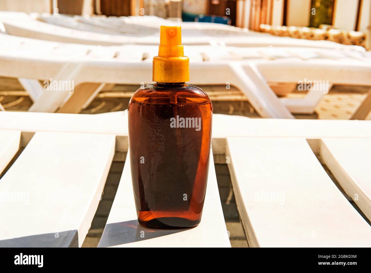 Flasche mit Sonnencreme auf weißem Liegestuhl. Konzept zur Vorbeugung von Sonnenbrand und Krebs. Platz zum Kopieren. Platz für Text auf der Flasche. Sonnenöl. Stockfoto