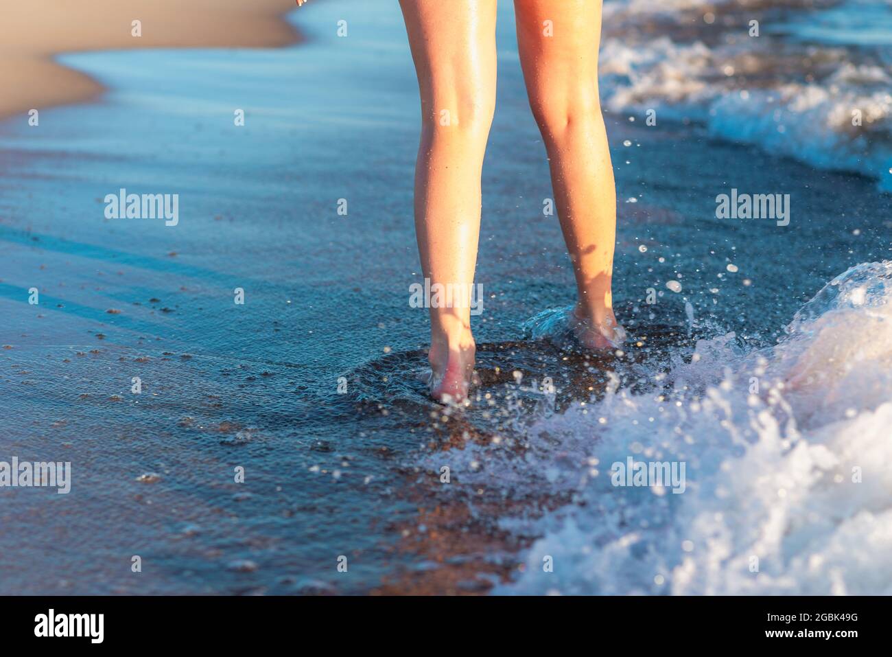 Frau Beine und Füße, die auf dem Sand des Strandes mit dem Meerwasser im Hintergrund zu Fuß auf dem Strand. Nahaufnahme von Beinen, die am Meer entlang laufen Stockfoto