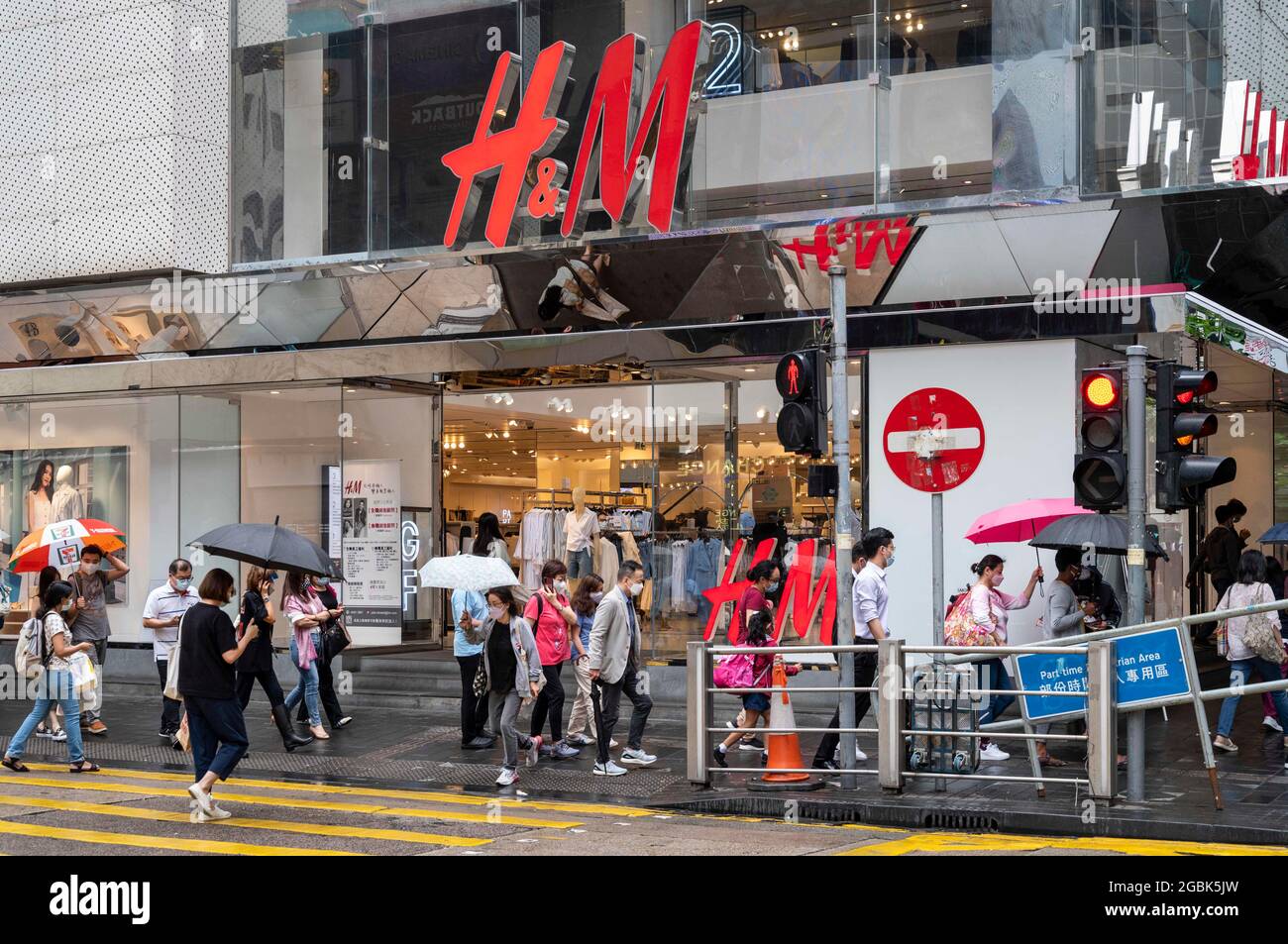 Hongkong, China. Mai 2021. Fußgänger schützen sich vor dem Regen, als sie die Straße vor dem schwedischen multinationalen Bekleidungsdesign-Einzelhandelsunternehmen Hennes & Mauritz, H&M, in Hongkong überqueren (Foto: © Budrul Chukrut/SOPA Images via ZUMA Press Wire) Stockfoto