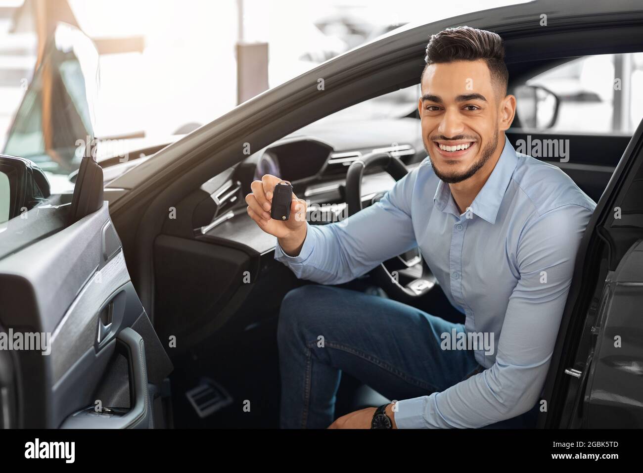 Hübscher arabischer Mann, der im Auto sitzt und den Schlüssel hält Stockfoto