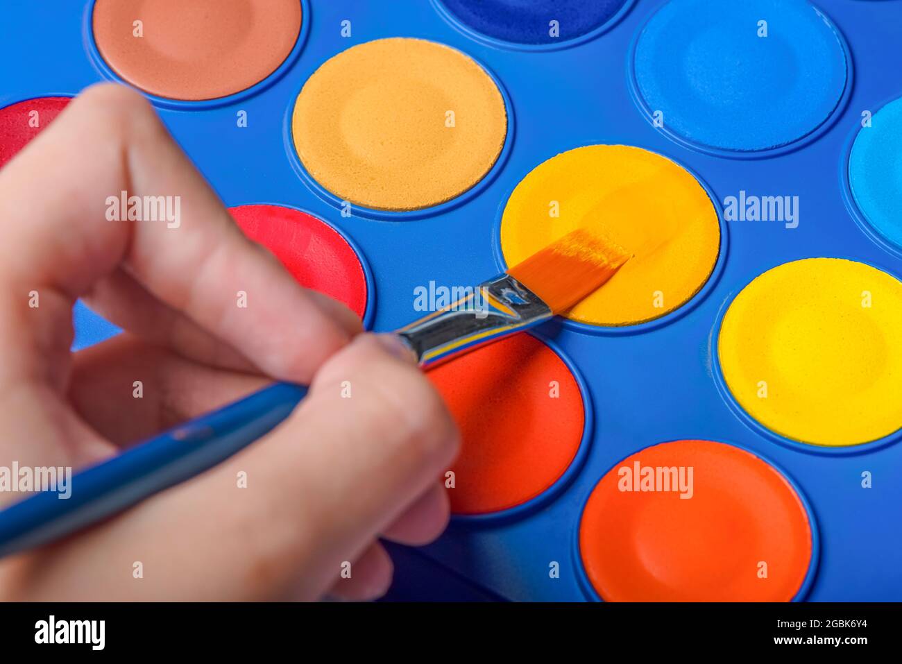 Ein Satz Aquarellfarben und ein Pinsel zum Zeichnen von Nahaufnahme. Kinderhand mit einem Pinsel. Selektiver Fokus. Stockfoto