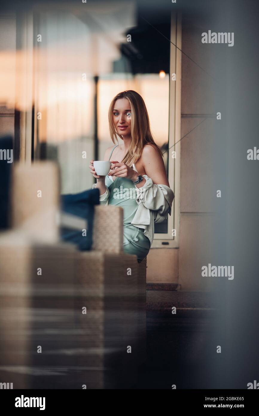 Entzückende kaukasische Frau sitzt und Frühstück mit einer Tasse Kaffee Stockfoto