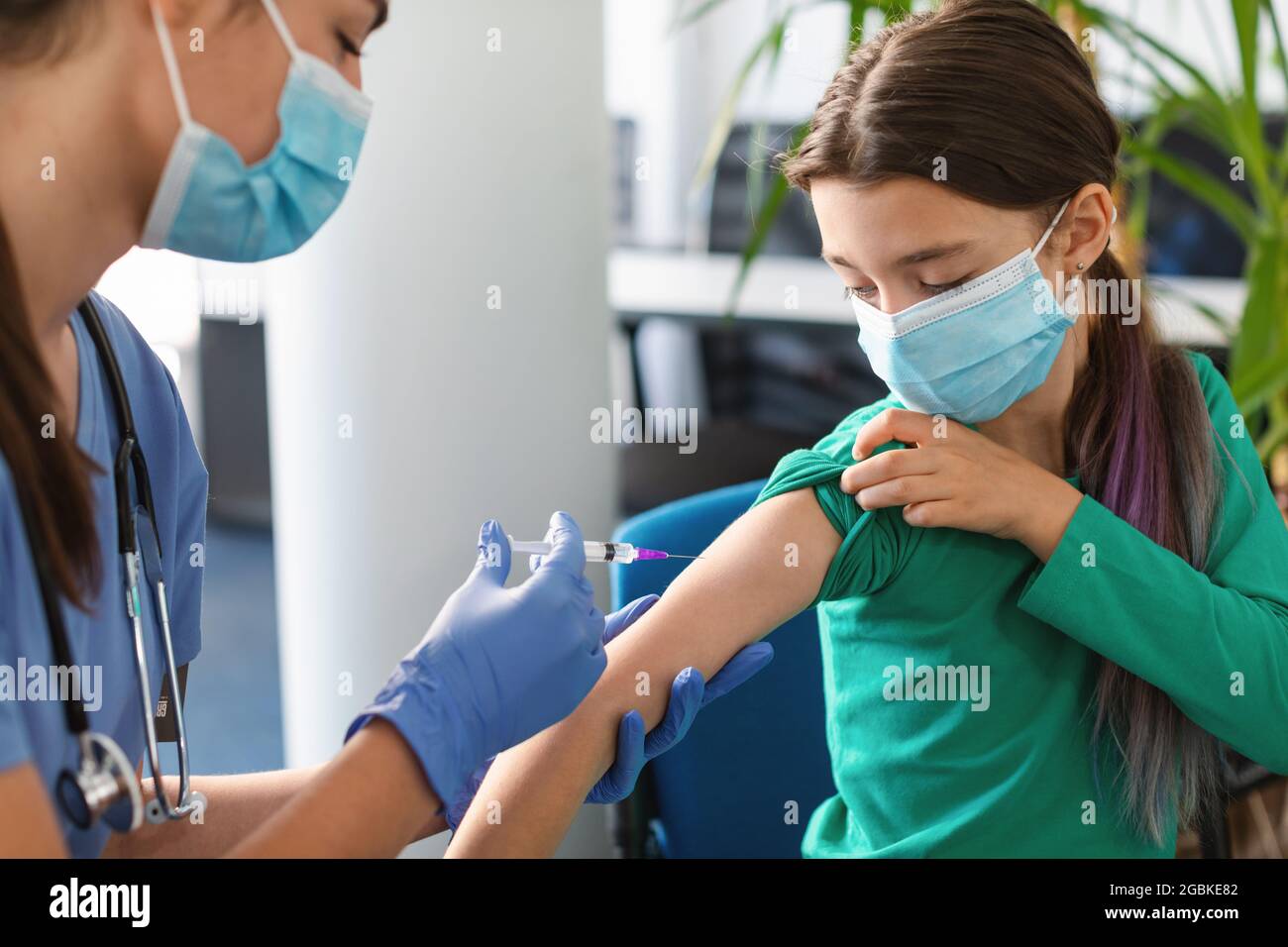 Schülerin Erhält Coronavirus-Impfstoff-Injektion Sitzt Mit Arzt In Der Halle Stockfoto