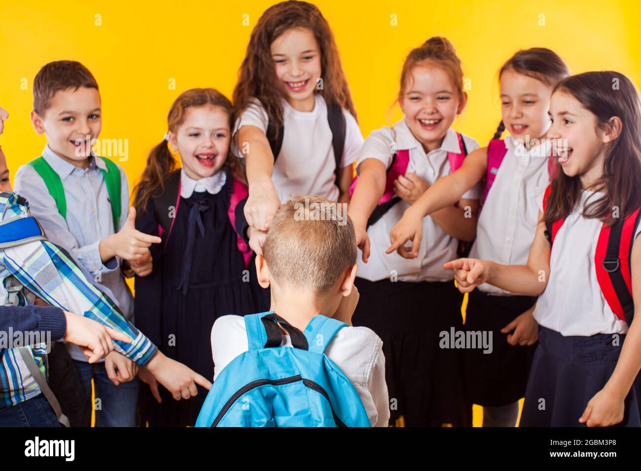 Die Klassenkameraden zeigen auf den Jungen und lachen ihn aus Stockfoto