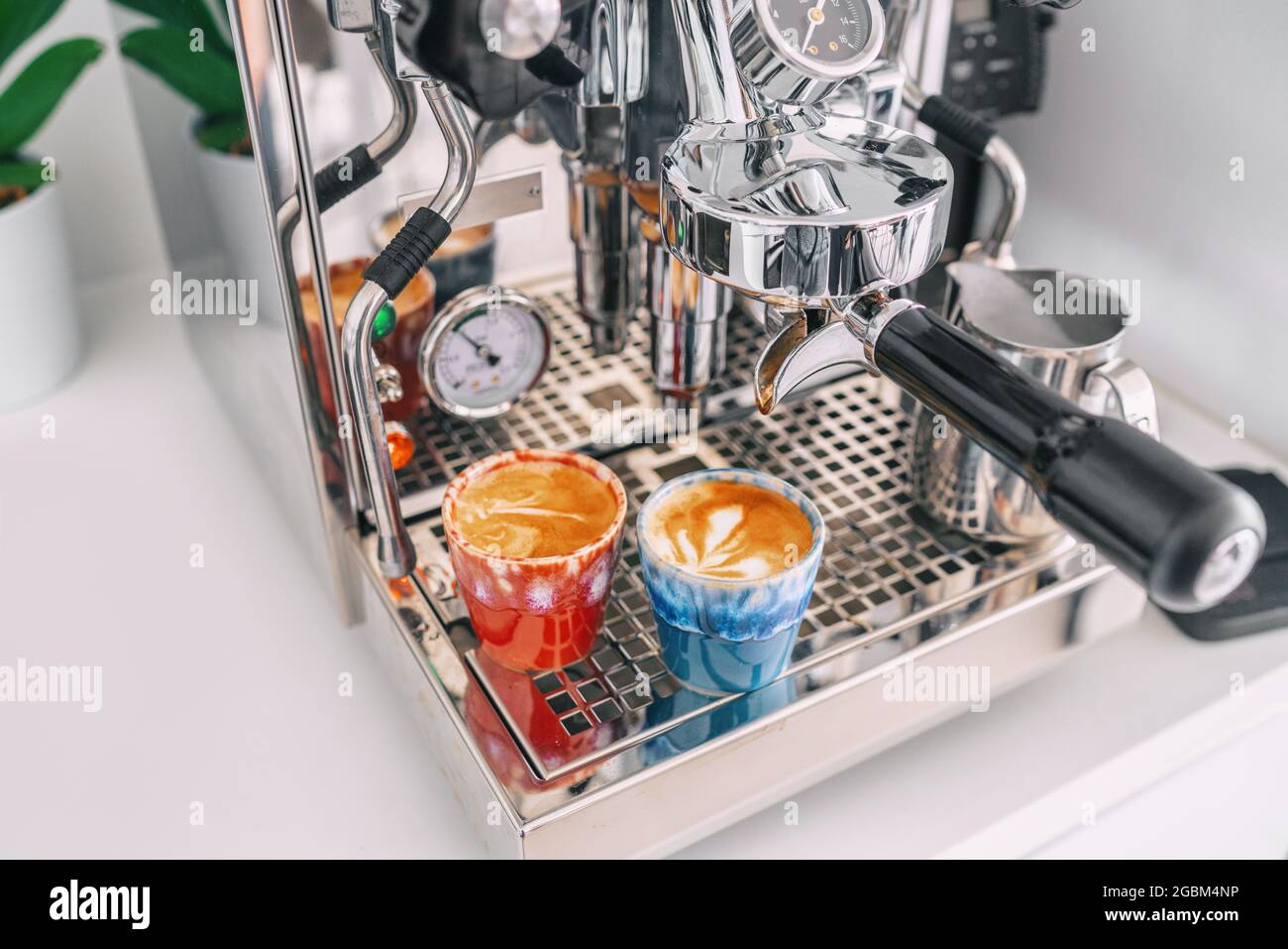 Zwei Macchiato-Shots in Espressotassen auf der Kaffeemaschine zu Hause - weiße Wohnküche, moderner Interieur-Lifestyle Stockfoto