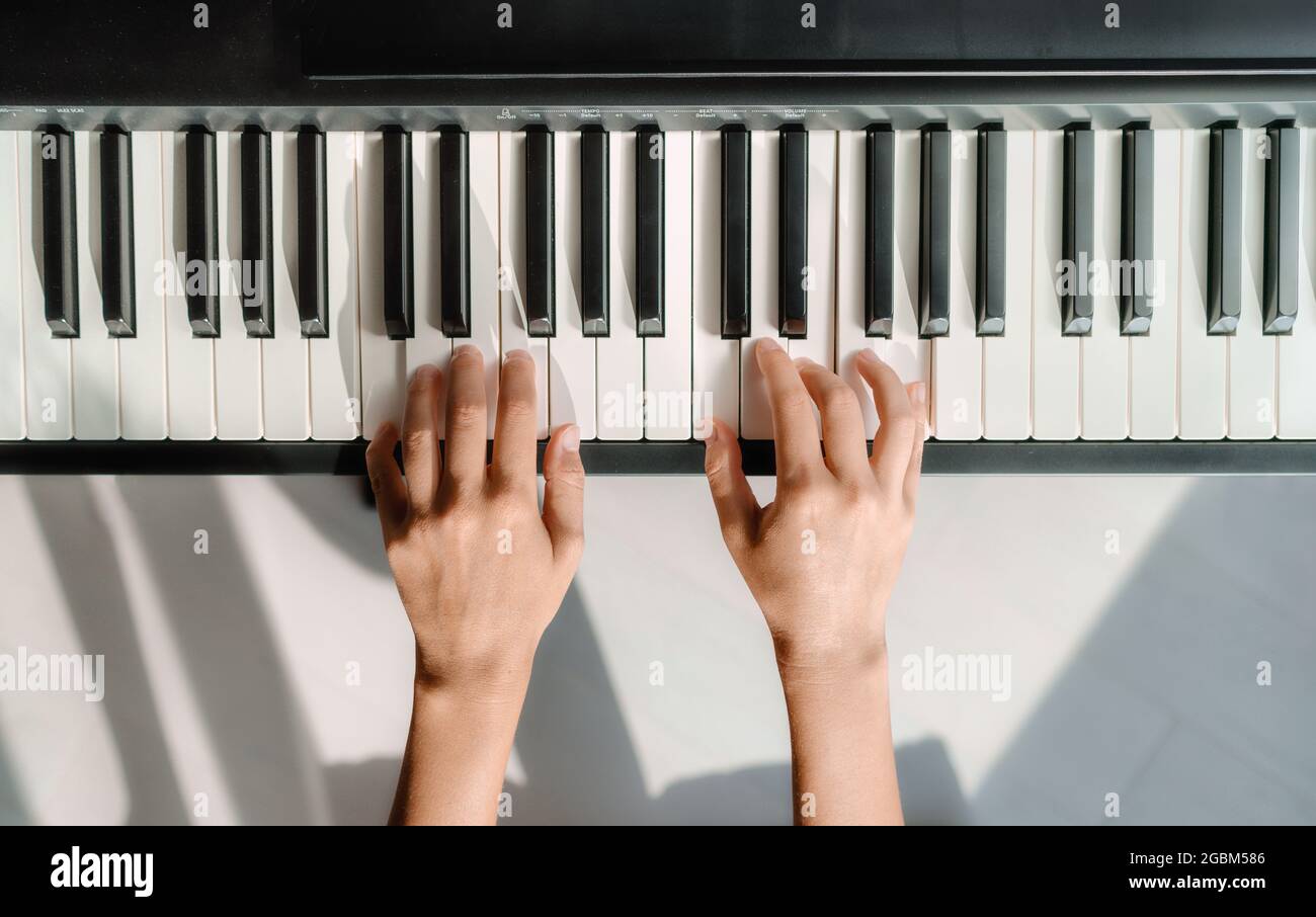 Klavier Akkorde zu Hause lernen - Frau spielt digitale Tastatur mit Online-Musikunterricht.  Draufsicht auf die Hände des Musikers auf den Tasten Stockfotografie - Alamy