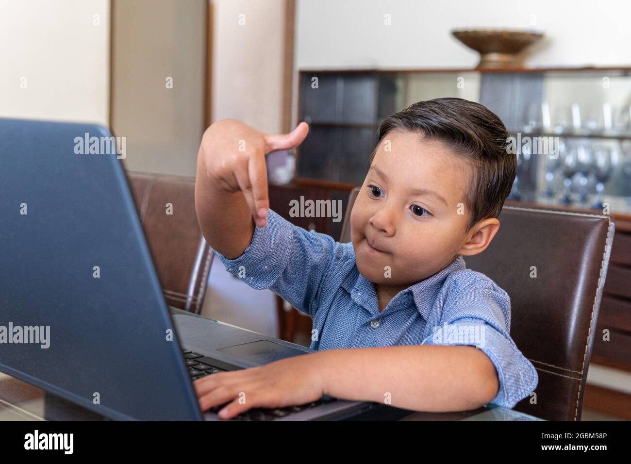 Vier Jahre alter Junge, der zu Hause mit einem Laptop interagiert Stockfoto