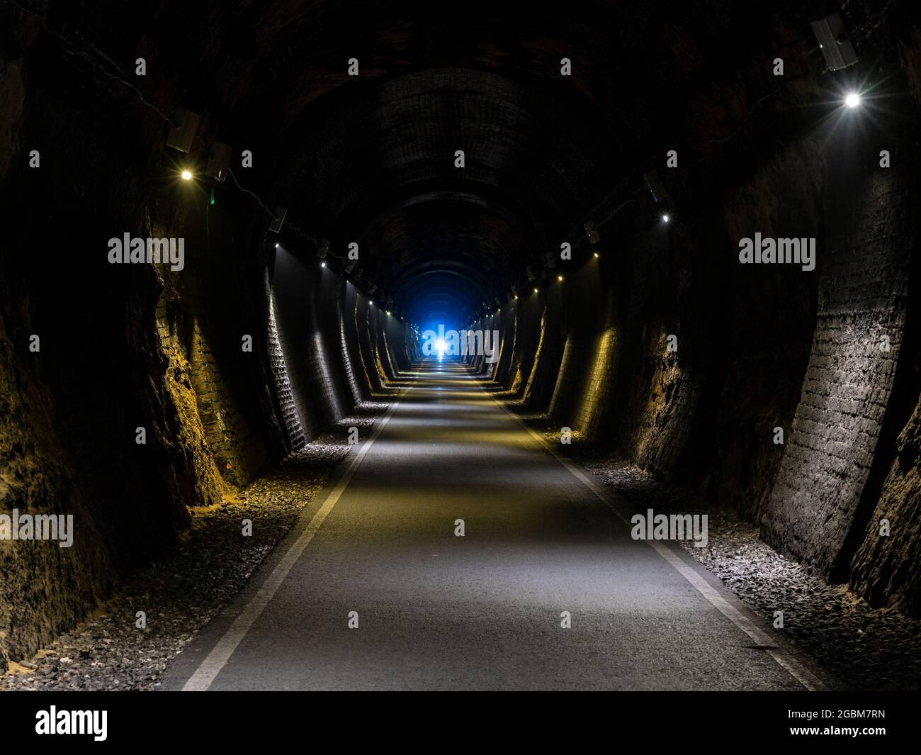 Im dunklen Combe Down Tunnel, Teil der beiden Tunnel Greenway Rail Trail in Bath, Somerset, leuchtet ein Radfahrerscheinwerfer. Stockfoto