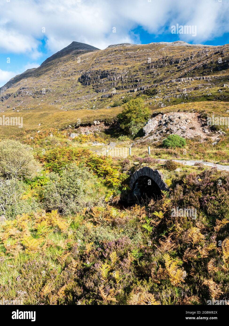 Eine steinerne Bogenbrücke führt die alte Route der A837 entlang der Flanken des Quinag Berges in Assynt, Schottland. Stockfoto