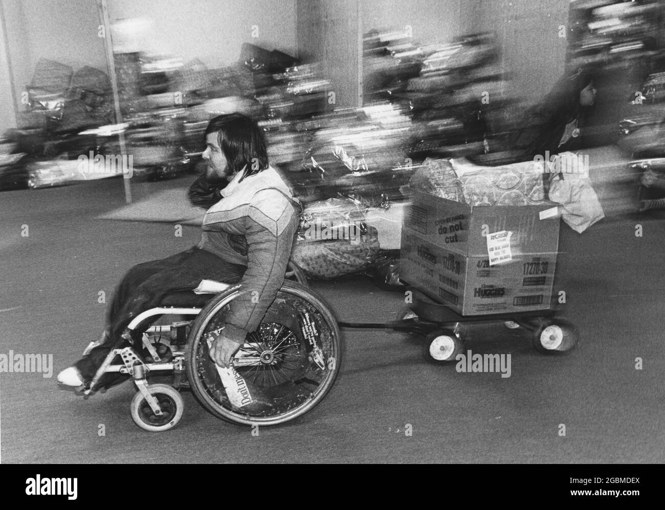 Austin, Texas, USA, um 1982: Ein behinderter Freiwilliger im Rollstuhl hilft bei der Vorbereitung von Spielzeug für die Verteilung an Kinder mit geringem Einkommen im Rahmen des Weihnachtsprogramms der Polizeibehörde von Austin, dem „Blauen Weihnachtsmann“. ©Bob Daemmrich Stockfoto