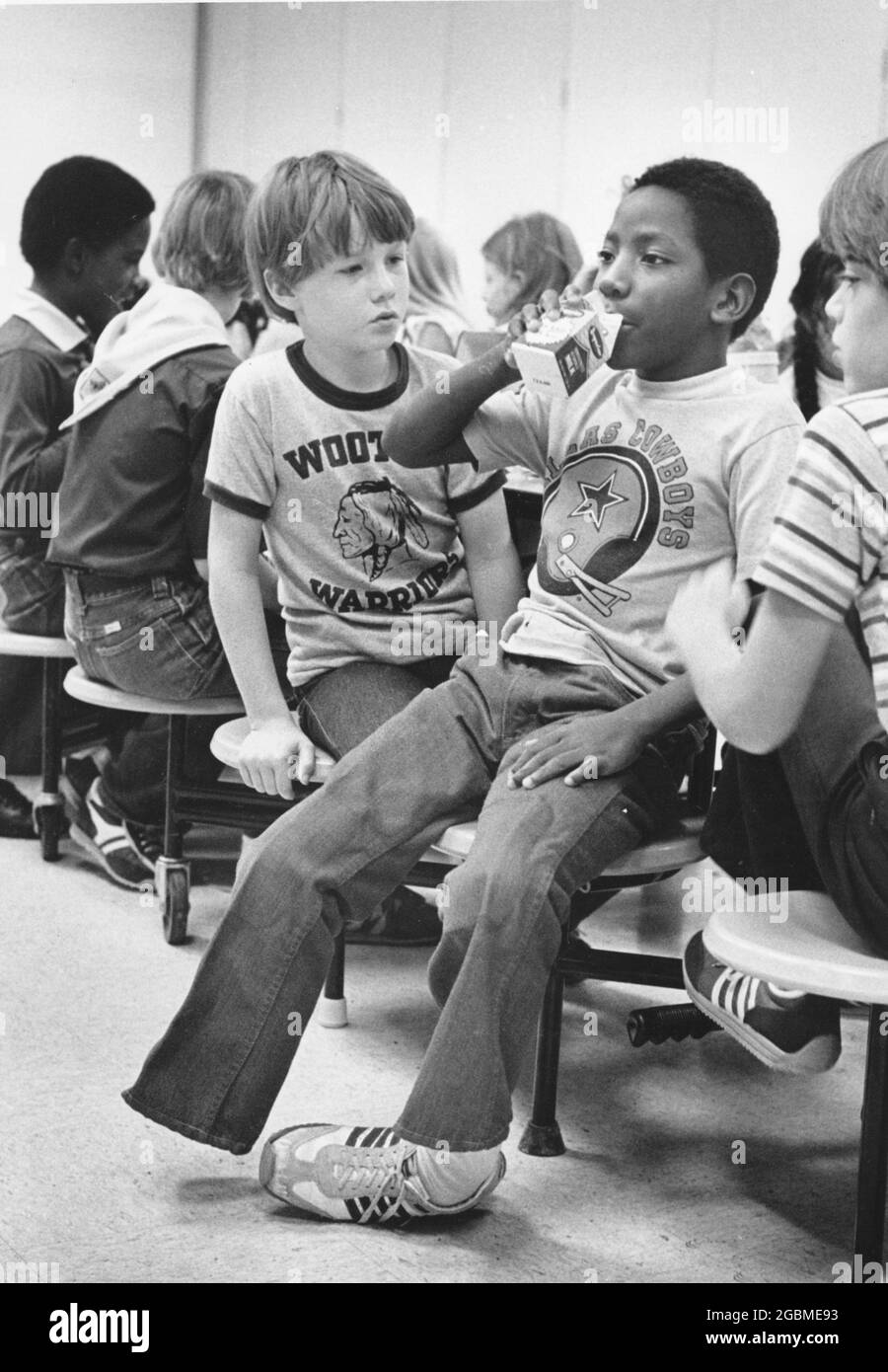 Austin, Texas, USA, um 1984: Der Junge der 4. Klasse Patrick Skeaton, der eine Spina bifida hat und in der 3. Klasse ein Bein amputiert haben musste. Die Fotogeschichte zeigt ihn an einem typischen Schultag; hier ist er mit einem neugierigen Mitschüler zur Mittagszeit in der Schulkantine, ohne sein prothetisches Bein zu tragen. ©Bob Daemmrich Stockfoto