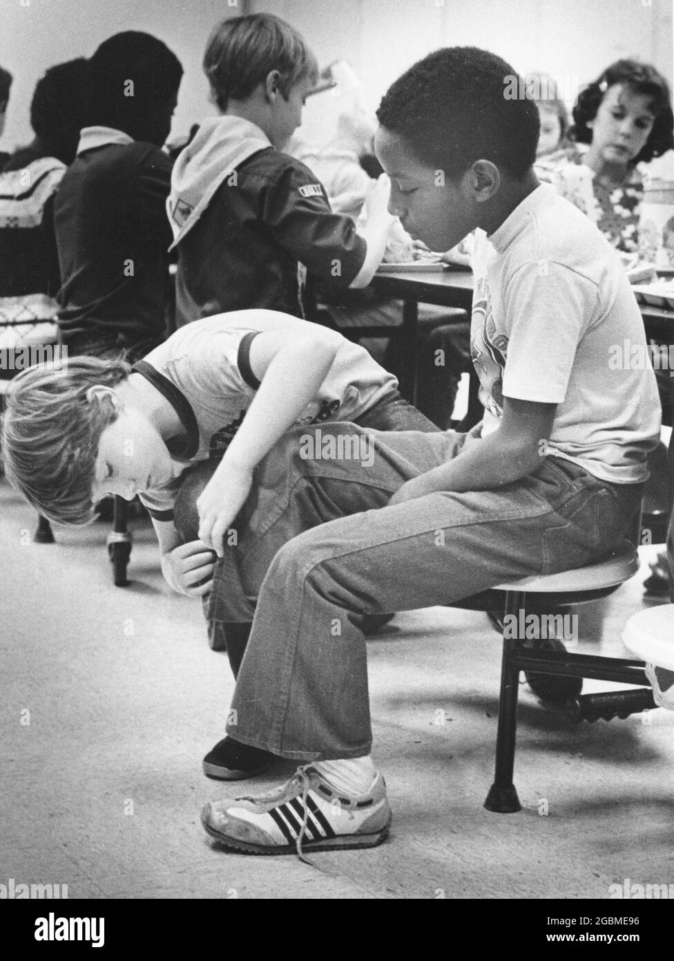 Austin, Texas, USA, um 1984: Der Junge der 4. Klasse Patrick Skeaton, der eine Spina bifida hat und in der 3. Klasse ein Bein amputiert haben musste. Die Fotogeschichte zeigt ihn an einem typischen Schultag; hier ist er mit einem neugierigen Mitschüler zur Mittagszeit in der Schulkantine, ohne sein prothetisches Bein zu tragen. ©Bob Daemmrich Stockfoto