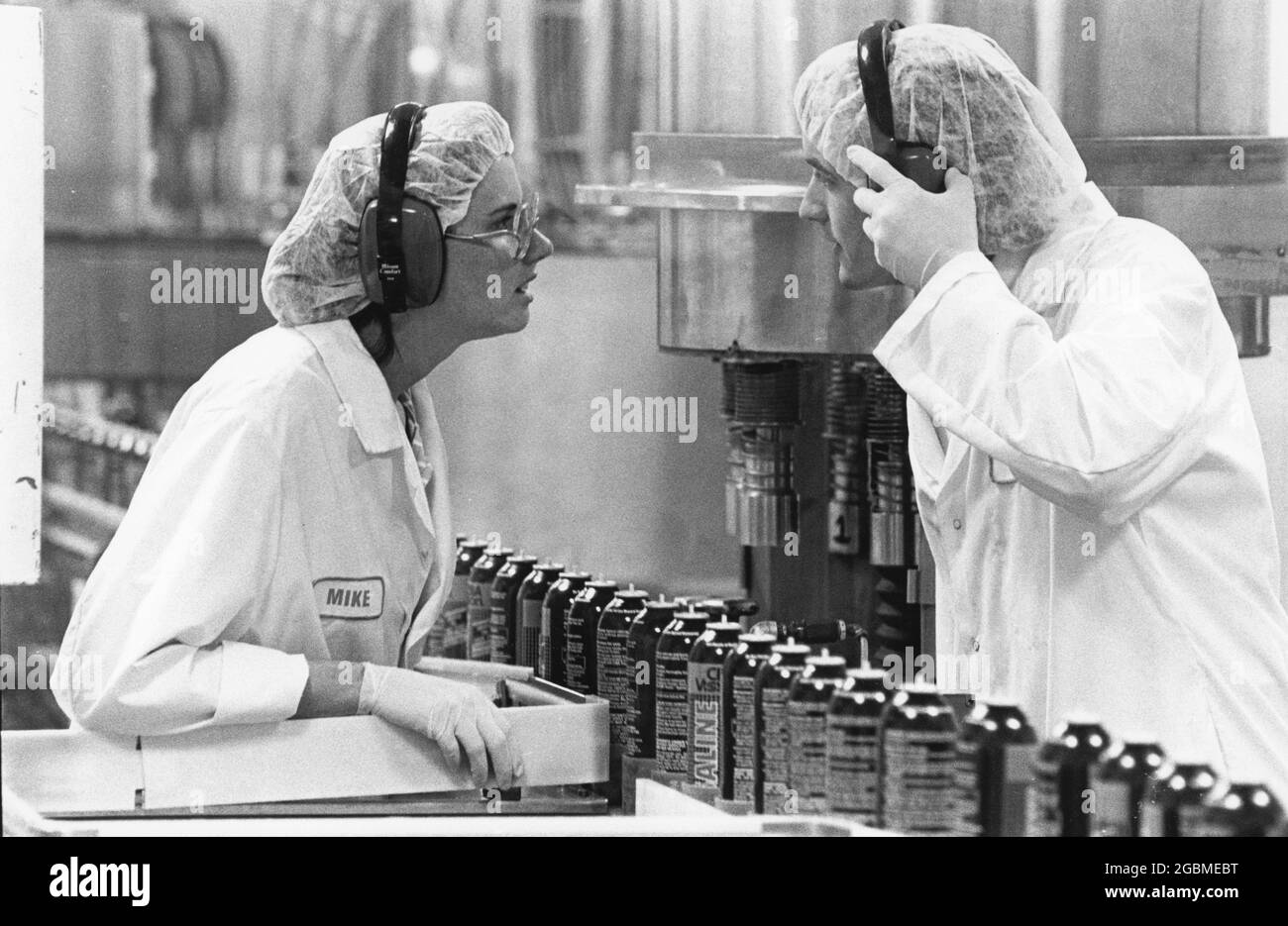 Waco Texas USA, um 1992: Mitarbeiter, die Schutzausrüstung wie Handschuhe, Haarnetze, Laborkittel und Gehörschutz tragen, sprechen über die Produktionslinie im Pharmawerk Allergan. ©Bob Daemmrich EH-0225 Stockfoto