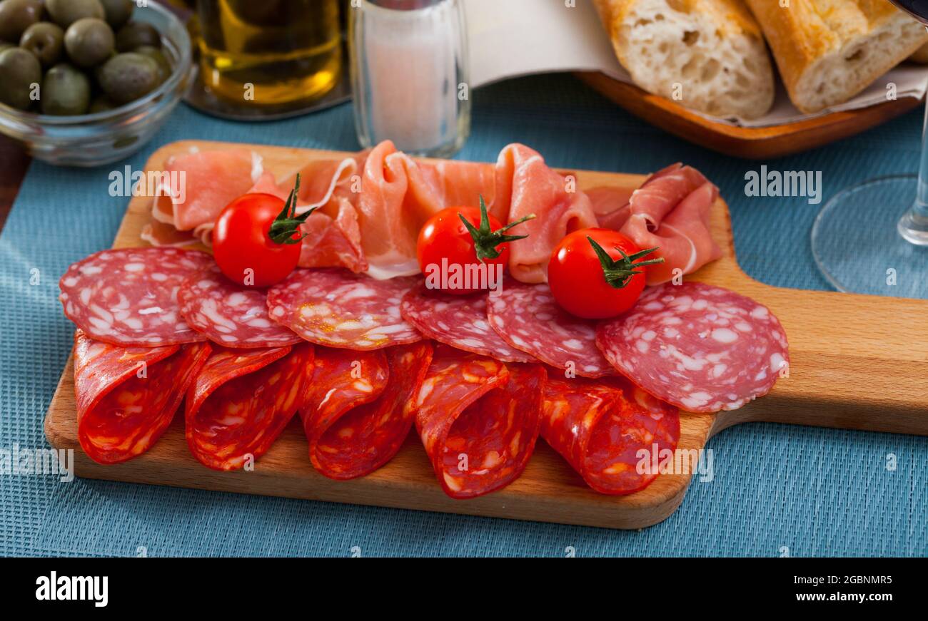 Spanische leckere Mahlzeit Würste und Jamon mit Tomaten schneiden, Nahaufnahme Stockfoto