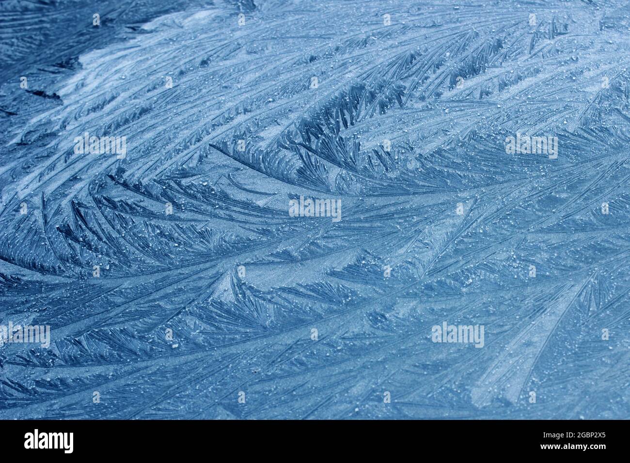 Frost blüht auf einer gefrorenen flachen Oberfläche in winterblauer Eismuster Hintergrundstruktur Stockfoto