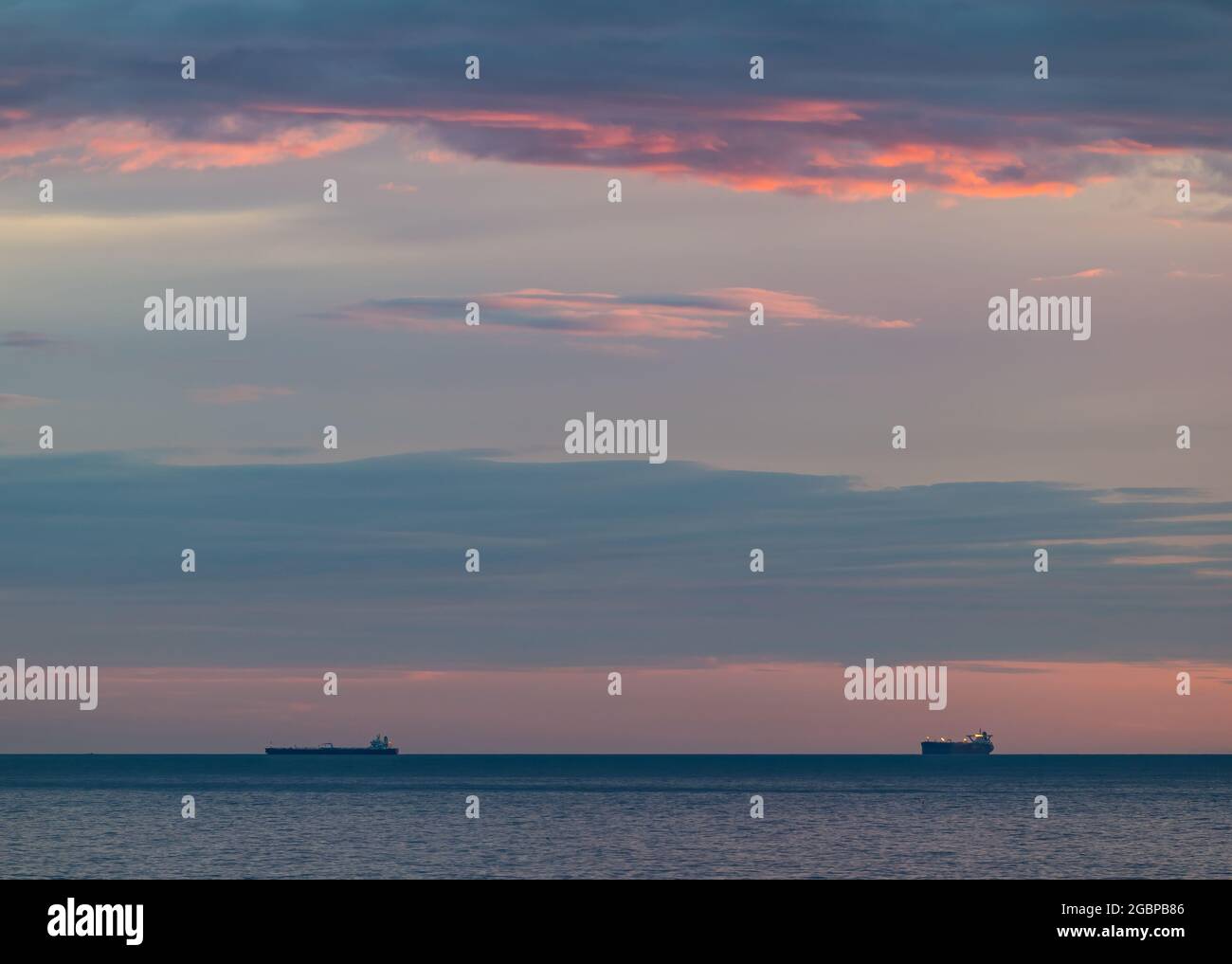 Schottland, Vereinigtes Königreich, 5. August 2021. Sonnenaufgang: Die Sonne geht über dem Horizont auf, die Silhouette der Frachtschiffe steht am Horizont in der Nordsee Stockfoto