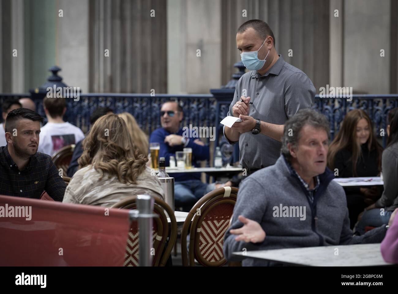 Foto vom 6/7/2020 eines Kellners, der Bestellungen in einem Restaurantbereich im Stadtzentrum von Glasgow entgegennimmt. Laut einem neuen Bericht verließen im vergangenen Jahr mehr als 90,000 EU-Arbeitnehmer den britischen Gastgewerbe, nachdem sich die Belegschaft der Branche seit der Pandemie und dem Brexit stark verändert hat. Die Jobseite Caterer.com sagte, dass drei von fünf Arbeitgebern im Gastgewerbe jetzt mehr Bewerbungen von britischen Arbeitnehmern erhalten als je zuvor. Ausgabedatum: Donnerstag, 5. August 2021. Stockfoto