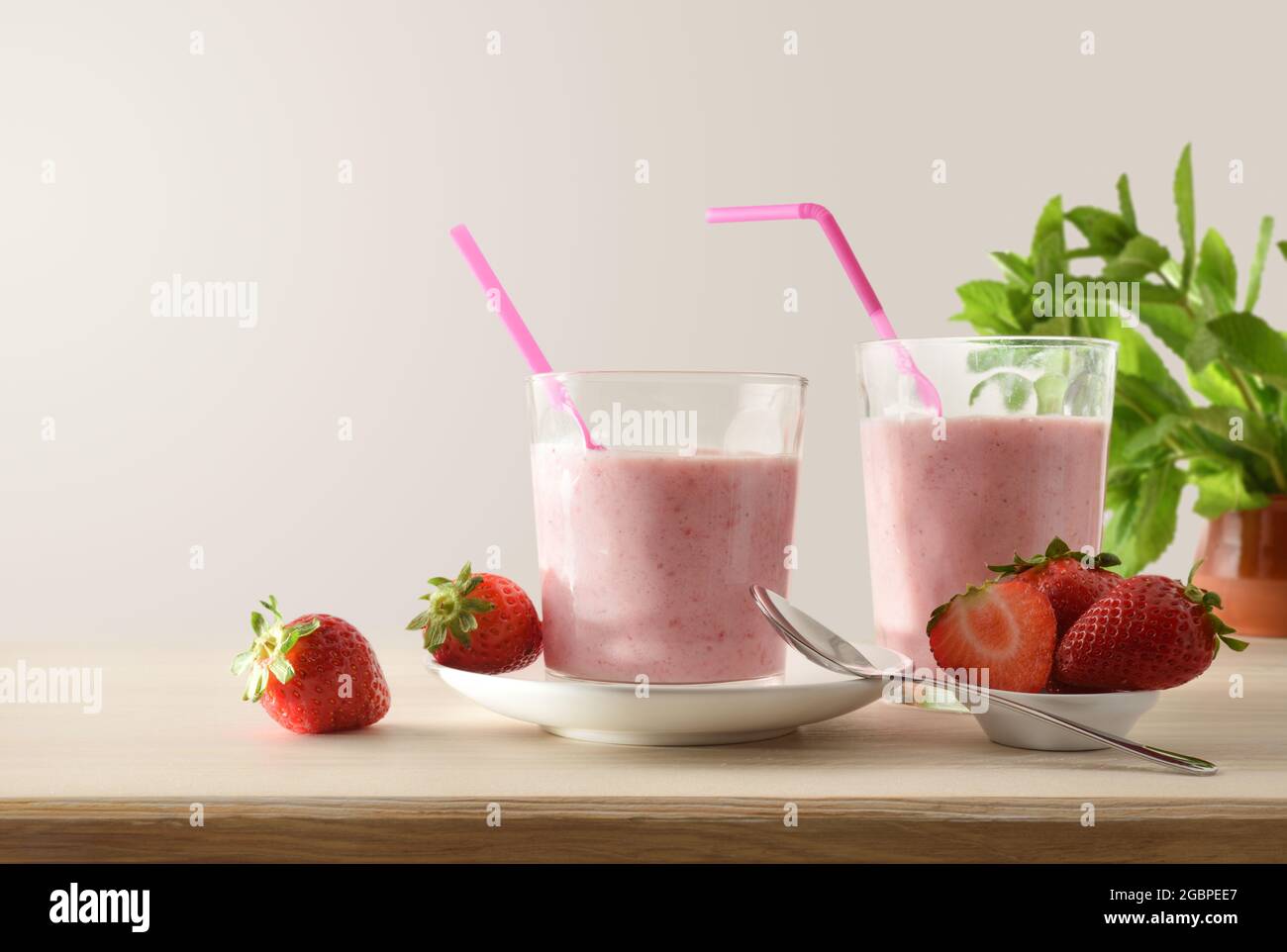 Gläser voller Erdbeer-Smoothie auf einem Holztisch voller Früchte isoliert Hintergrund. Vorderansicht. Stockfoto