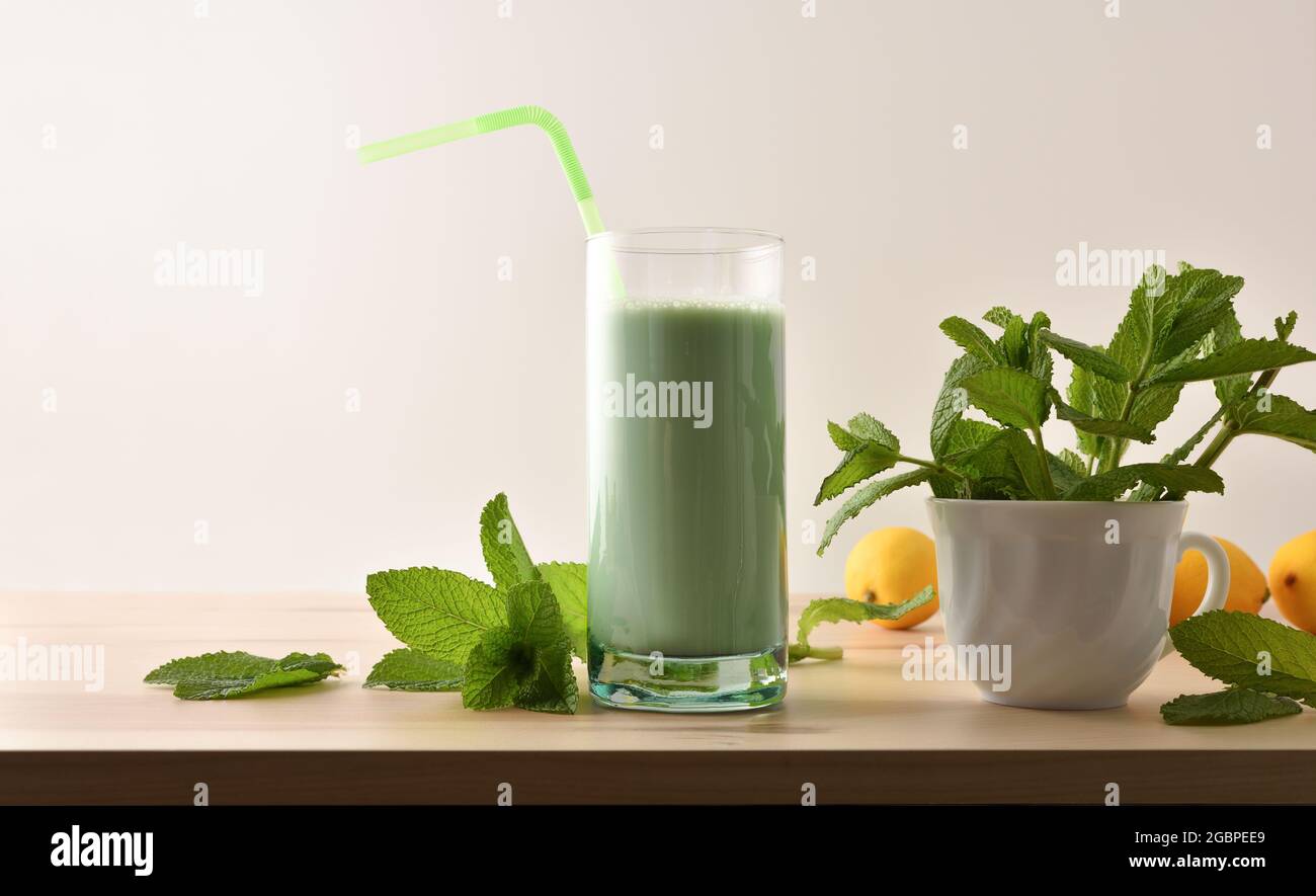 Milchshake mit Minze auf Holztisch und Minzblättern isolierter weißer Hintergrund Vorderansicht. Stockfoto
