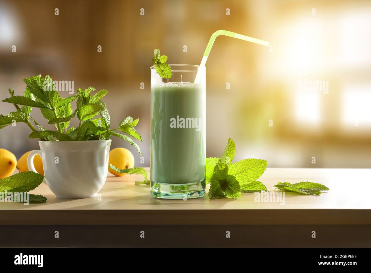 Milchshake mit Minze auf Holztisch und Minzblätter in rustikaler Küche. Vorderansicht. Stockfoto