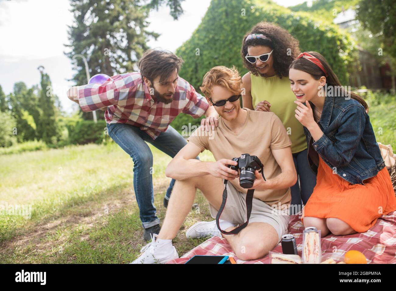 Freunde, die Fotos anschauen und sich beim Picknick ausruhen Stockfoto