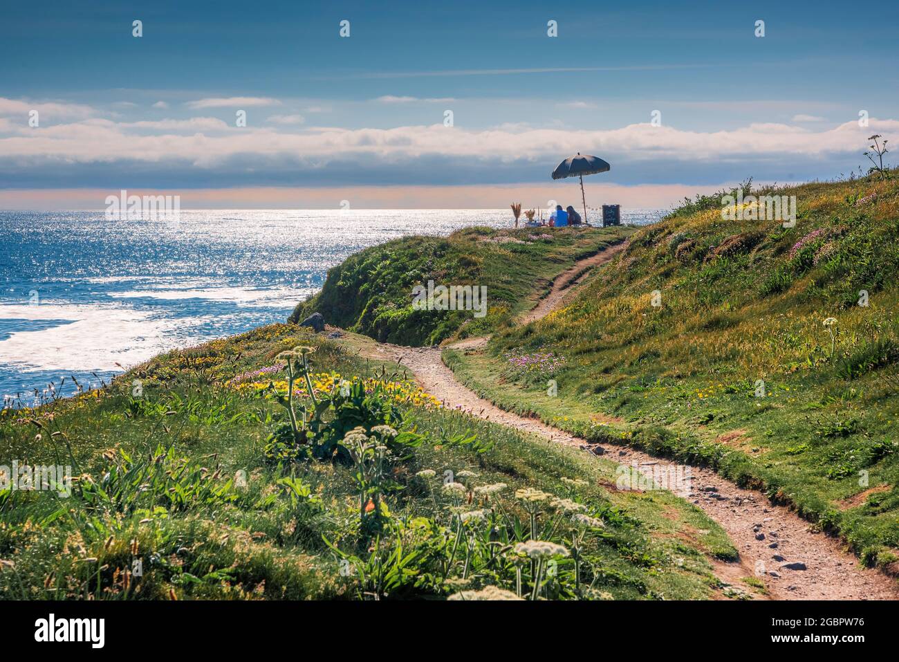 Ein junges Paar Urlauber feiert einen romantischen Anlass mit einem stilvollen Picknick im Freien auf Towan Head mit Blick auf die Fistral Bay in Newquay in Corn Stockfoto