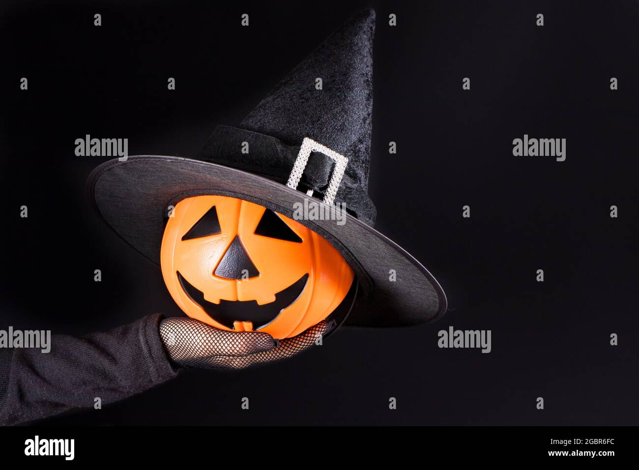 Eine Hand hält einen Kürbis Laterne Jack auf einem schwarzen. Accessoires für Halloween. Platz für Text kopieren Stockfoto