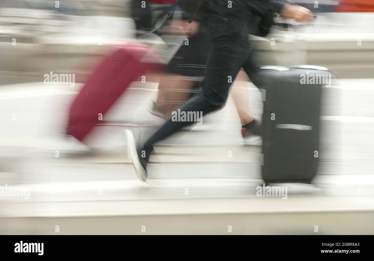 Reisende mit Gepäck und rollenden Koffern. Ankommen oder Abreisen, in Eile, symbolisches Bild, konzeptuell. Stockfoto