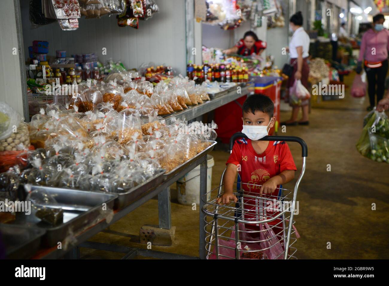 Vientian. August 2021. Ein maskiertes Kind schiebt am 4. August 2021 auf einem Markt in der laotischen Hauptstadt Vientiane einen Einkaufswagen. Die laotische Regierung hat beschlossen, die aktuelle landesweite Sperre bis zum 18. August zu verlängern, da die COVID-19-Fälle weiter zunehmen. Kredit: Kaikeo Saiyasane/Xinhua/Alamy Live Nachrichten Stockfoto