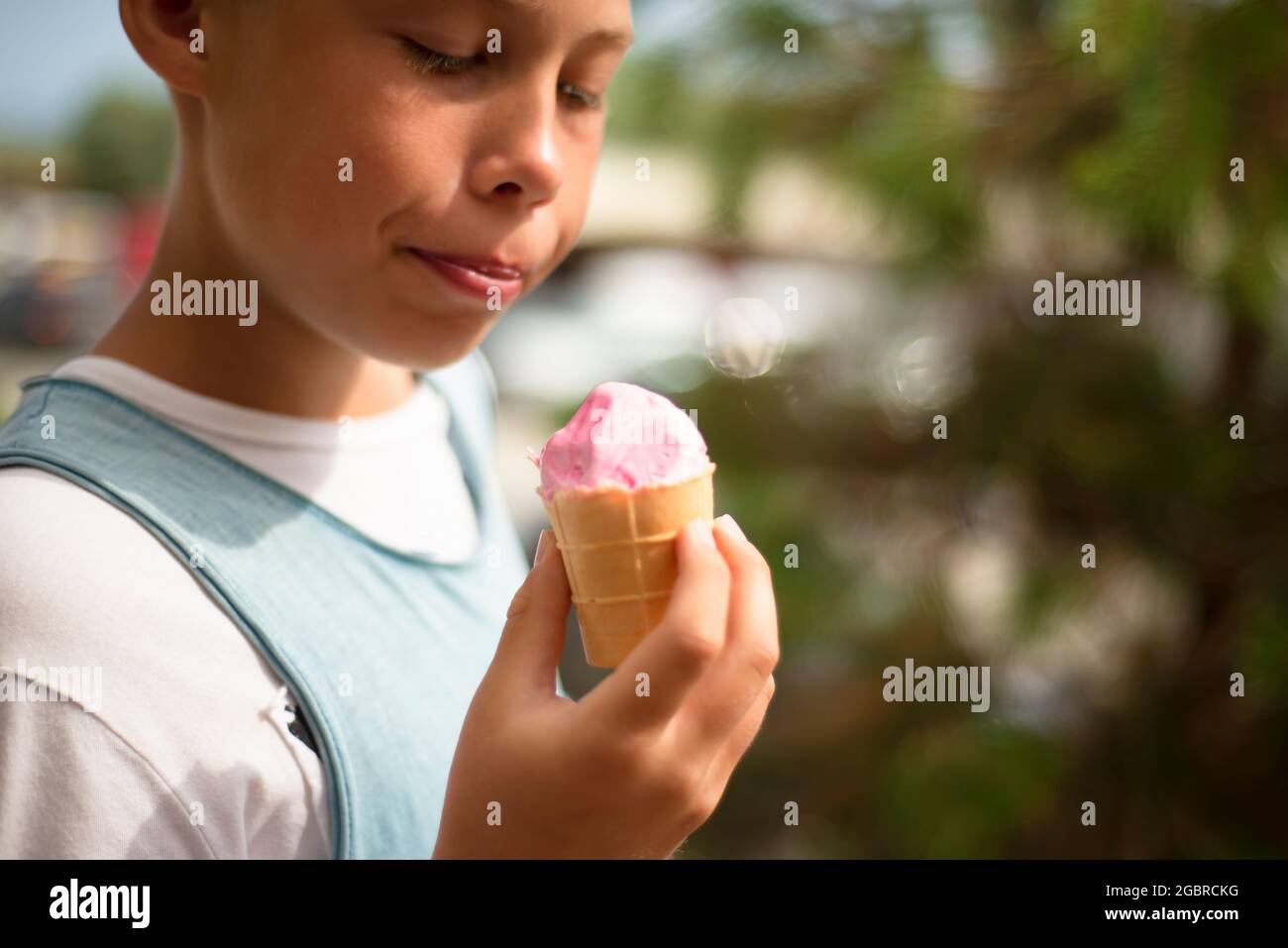 Der Junge hält ein rosa Eis in der Hand. Vergnügen. Positive Emotionen. Stockfoto