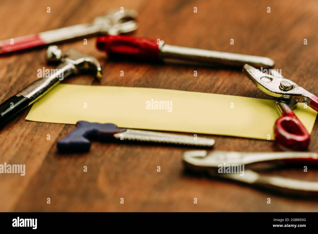 Bastelkonzept: Eine Haftnotiz, umgeben von Miniatur-Bastelwerkzeugen. Textbereich. Stockfoto