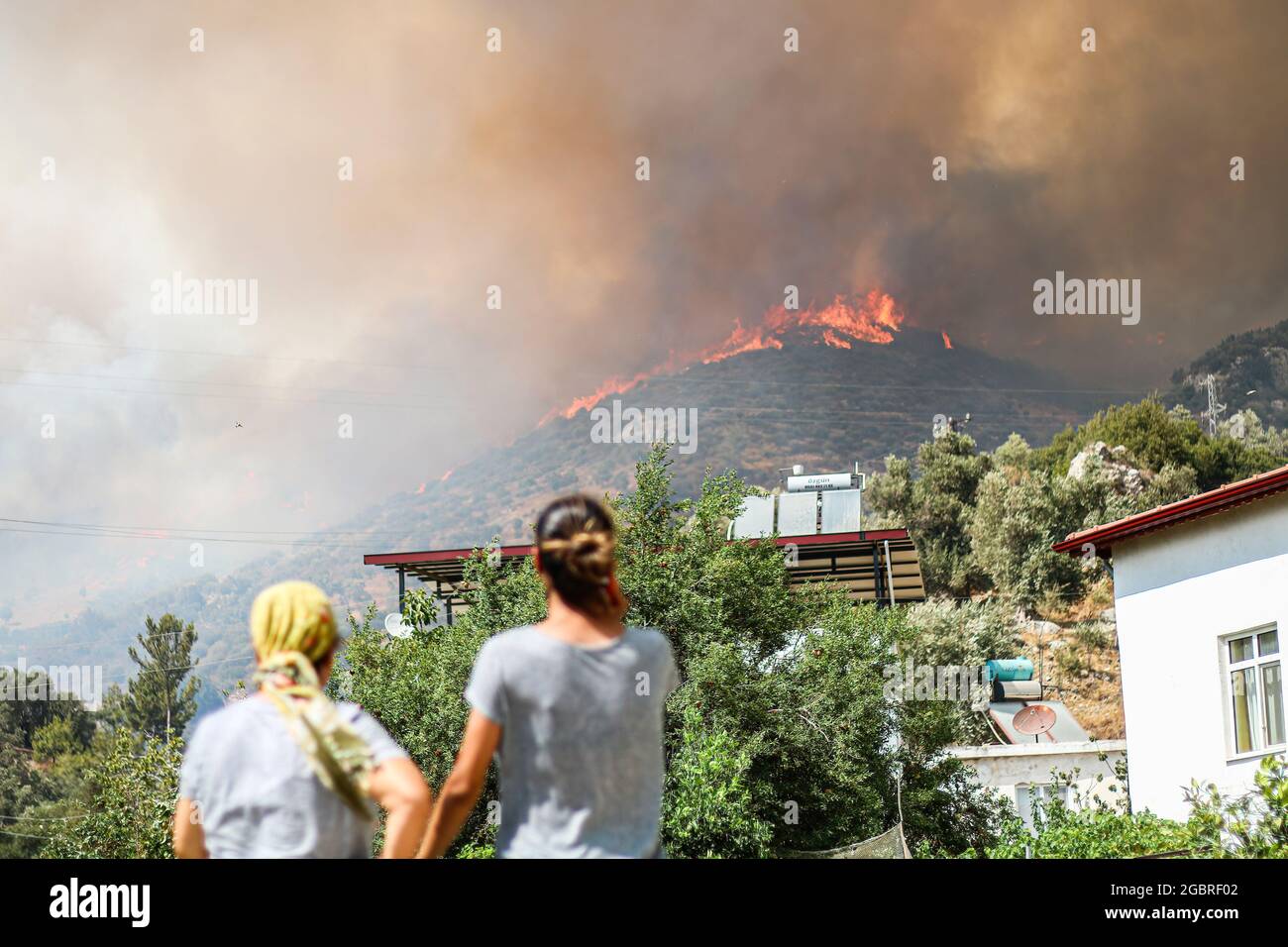 Menschen beobachten den Rauch, der aus dem Waldbrandbereich kommt. In den südlichen und südwestlichen Städten der Türkei setzt sich das vor 8 Tagen ausbrechende Wildfeuer fort. Der Distrikt Milas in Mugla gehört zu den am stärksten von den Bränden betroffenen Regionen. (Foto von Hakan Akgun/SOPA Images/Sipa USA) Quelle: SIPA USA/Alamy Live News Stockfoto